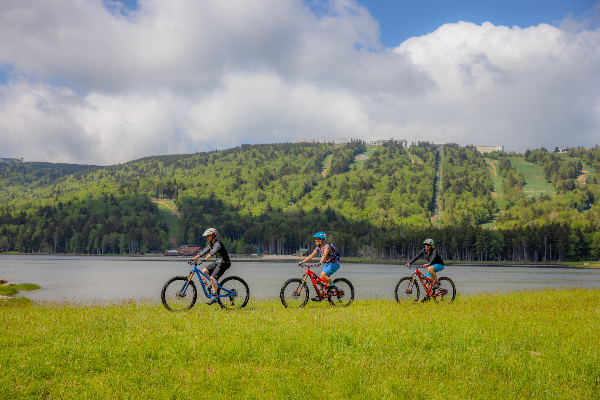 Group of people biking alongside lake on a summer day
