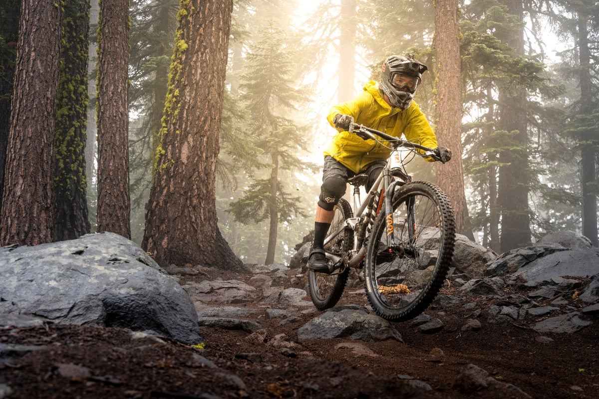 Biker with a helmet on riding along rocks in forest on a foggy day.