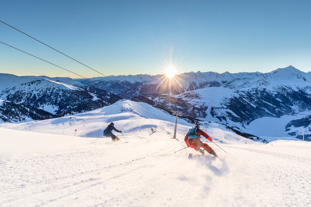 Lyžiari na zjazdovke v Zillertal Arene pri východe slnka