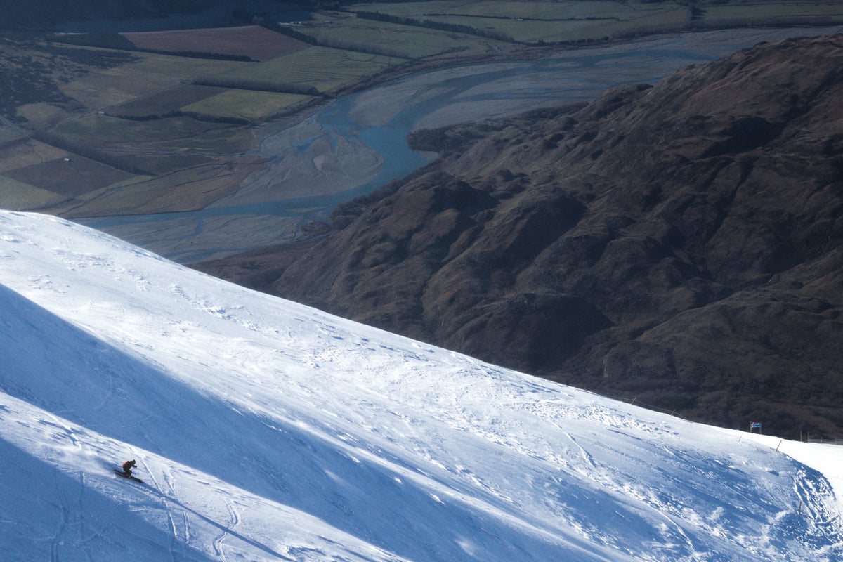 Person skiing down slopes of Treble Cone in Lake Wanaka on a sunny day