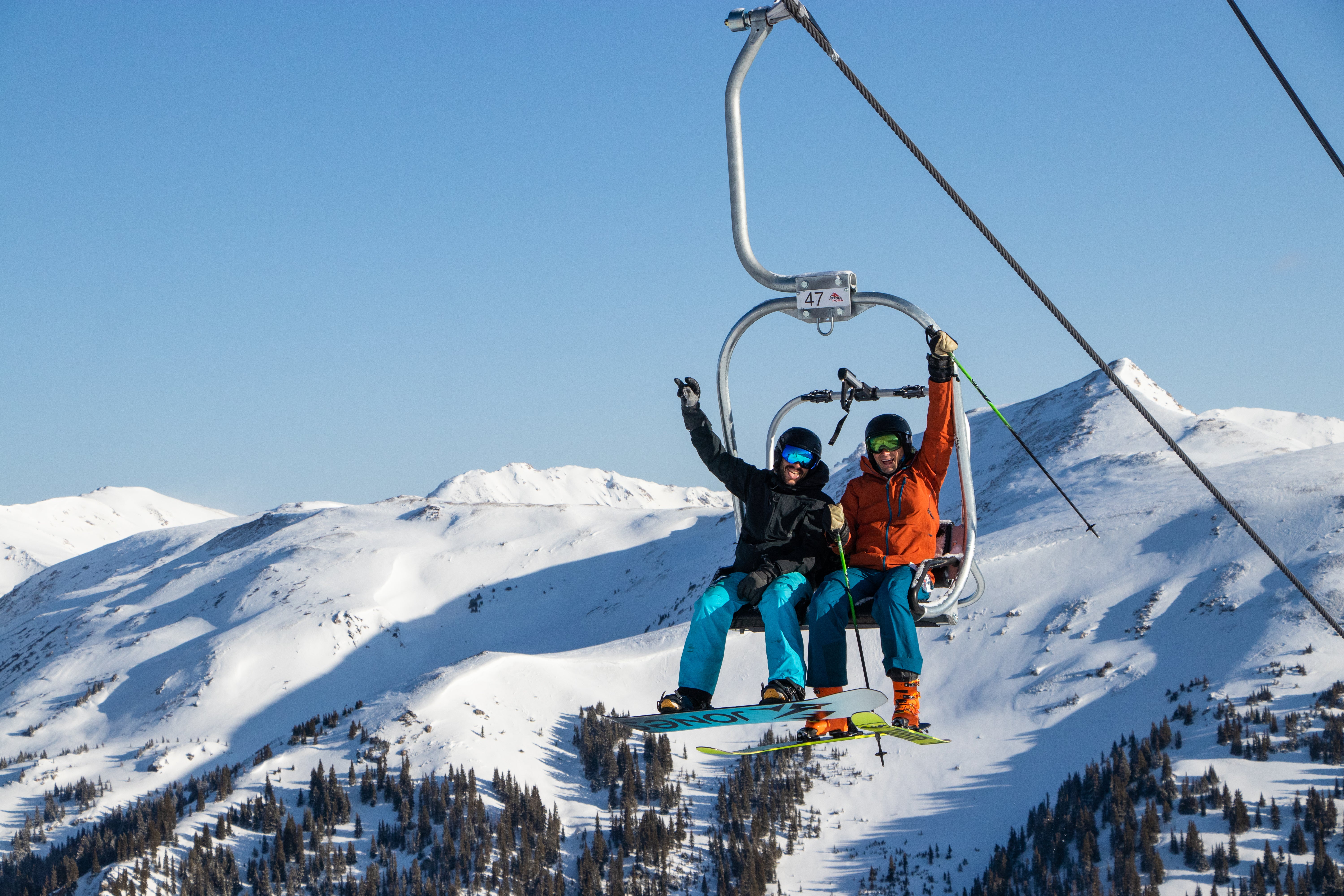 Two people waving from chairlift on a sunny day