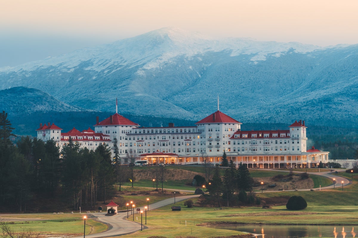 The Omni Mount Washington Resort at dusk with snow-dusted mountains behind it