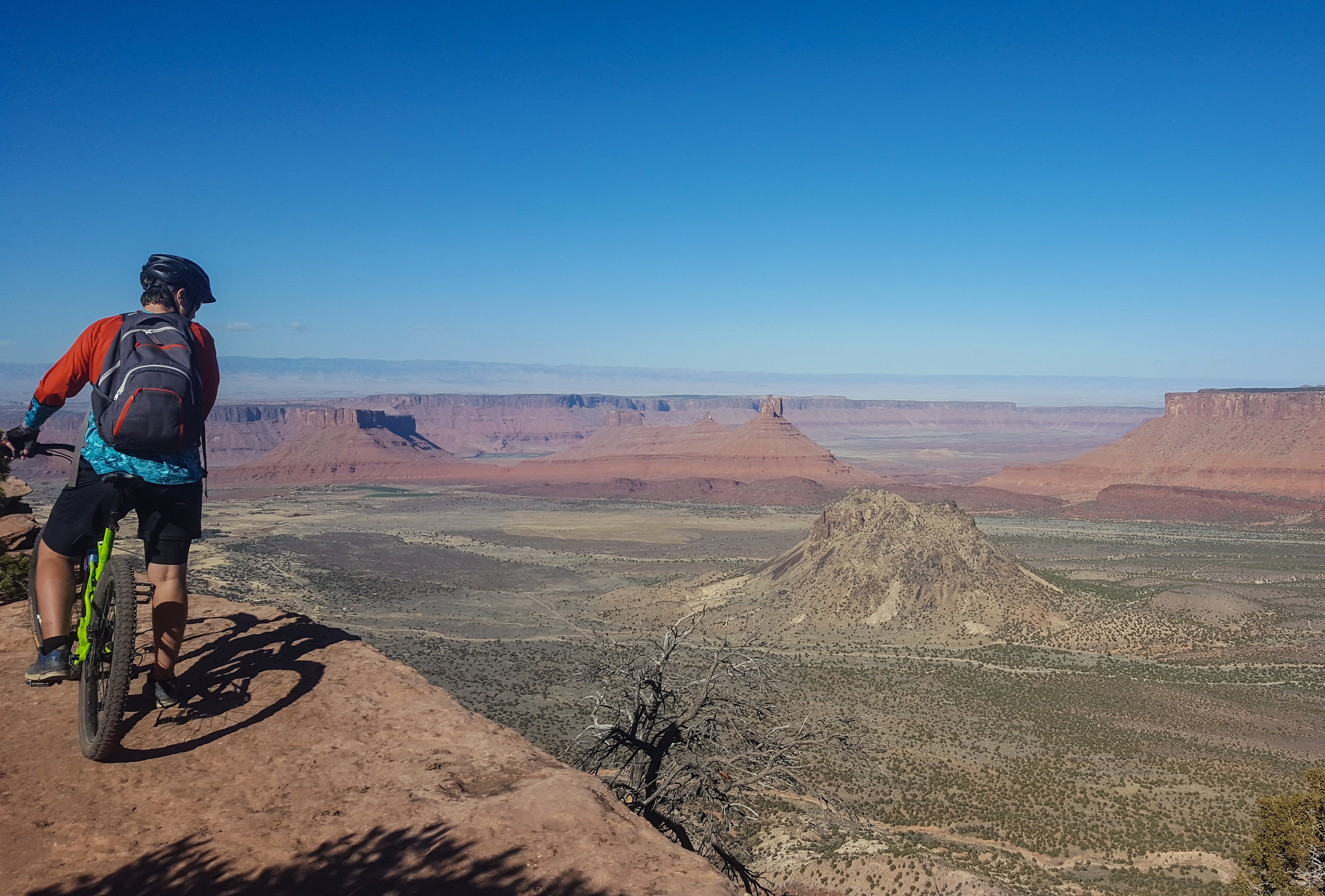 Biker at top of peak looking down at the valley
