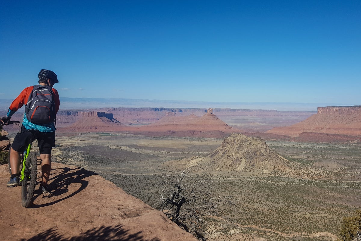 Biker at top of peak looking down at the valley