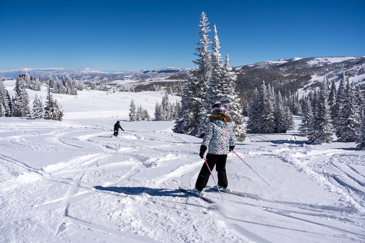 Two people skiing down blue run on a sunny day