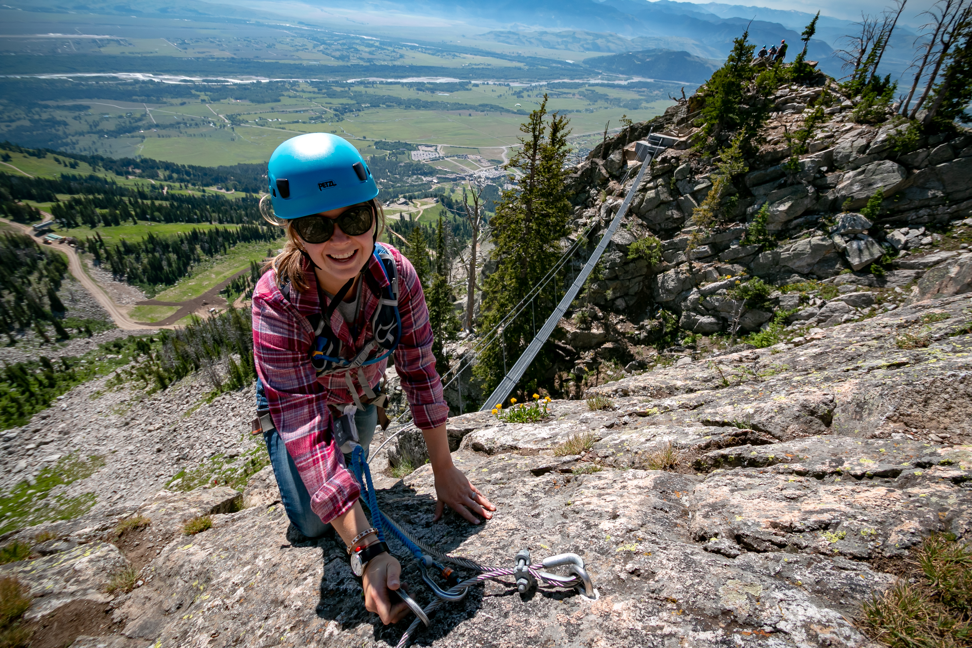 Woman smiling atop via ferrata on a sunny day