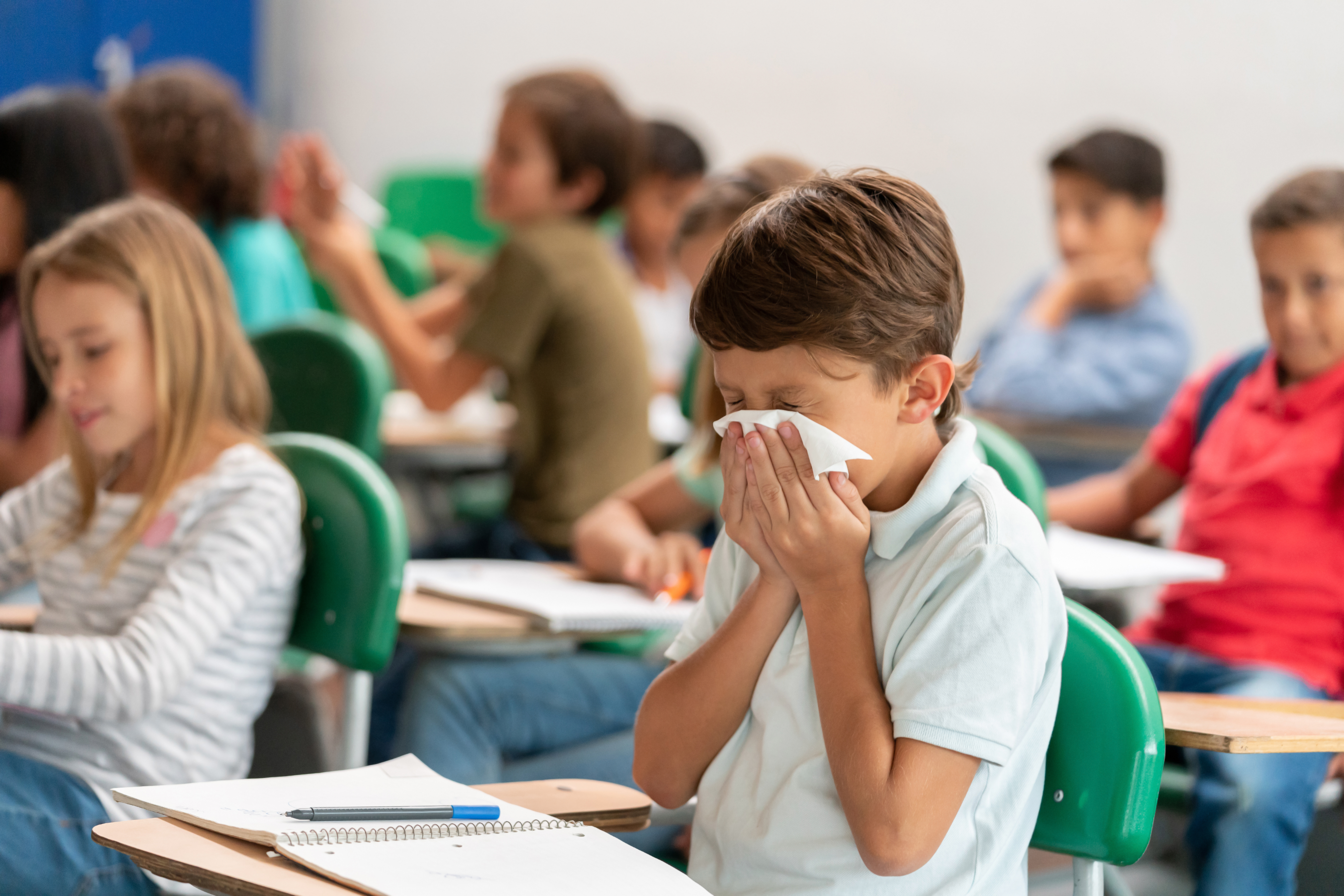 child using a tissue to catch a sneeze