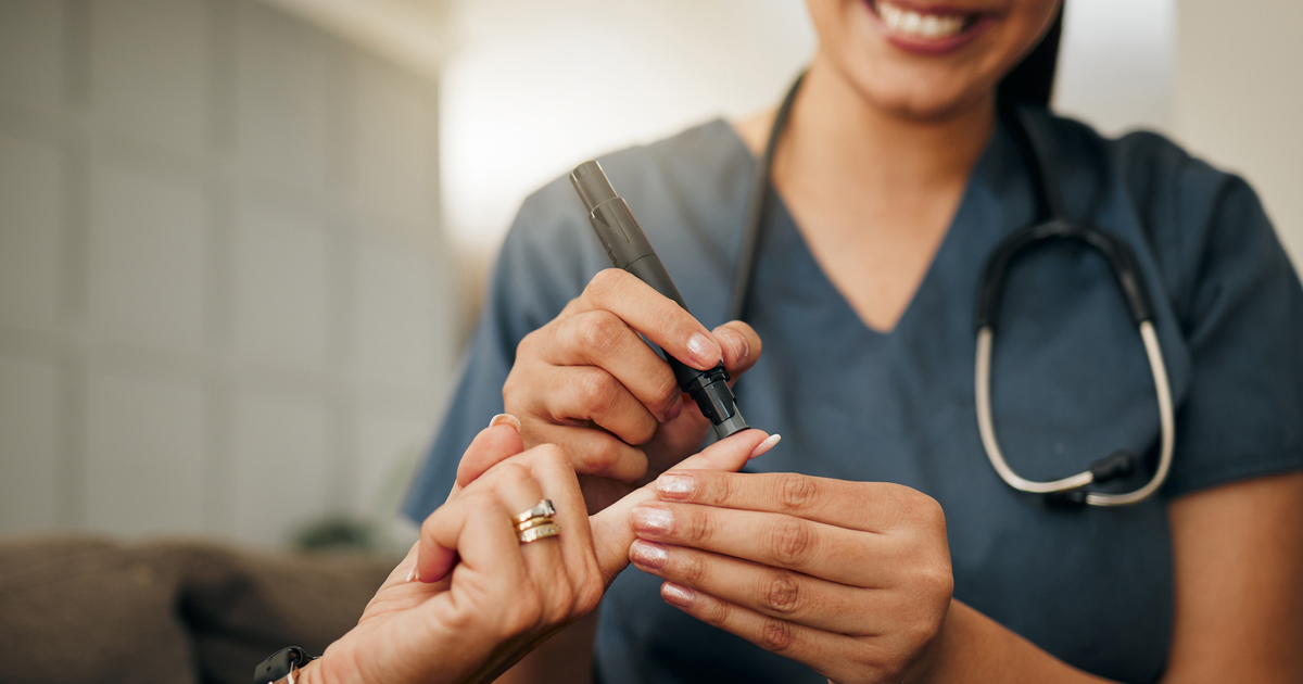Staff checking patient's blood glucose with finger poke.