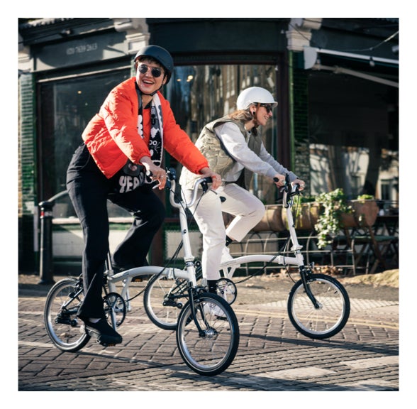 Two people riding Brompton bikes through London
