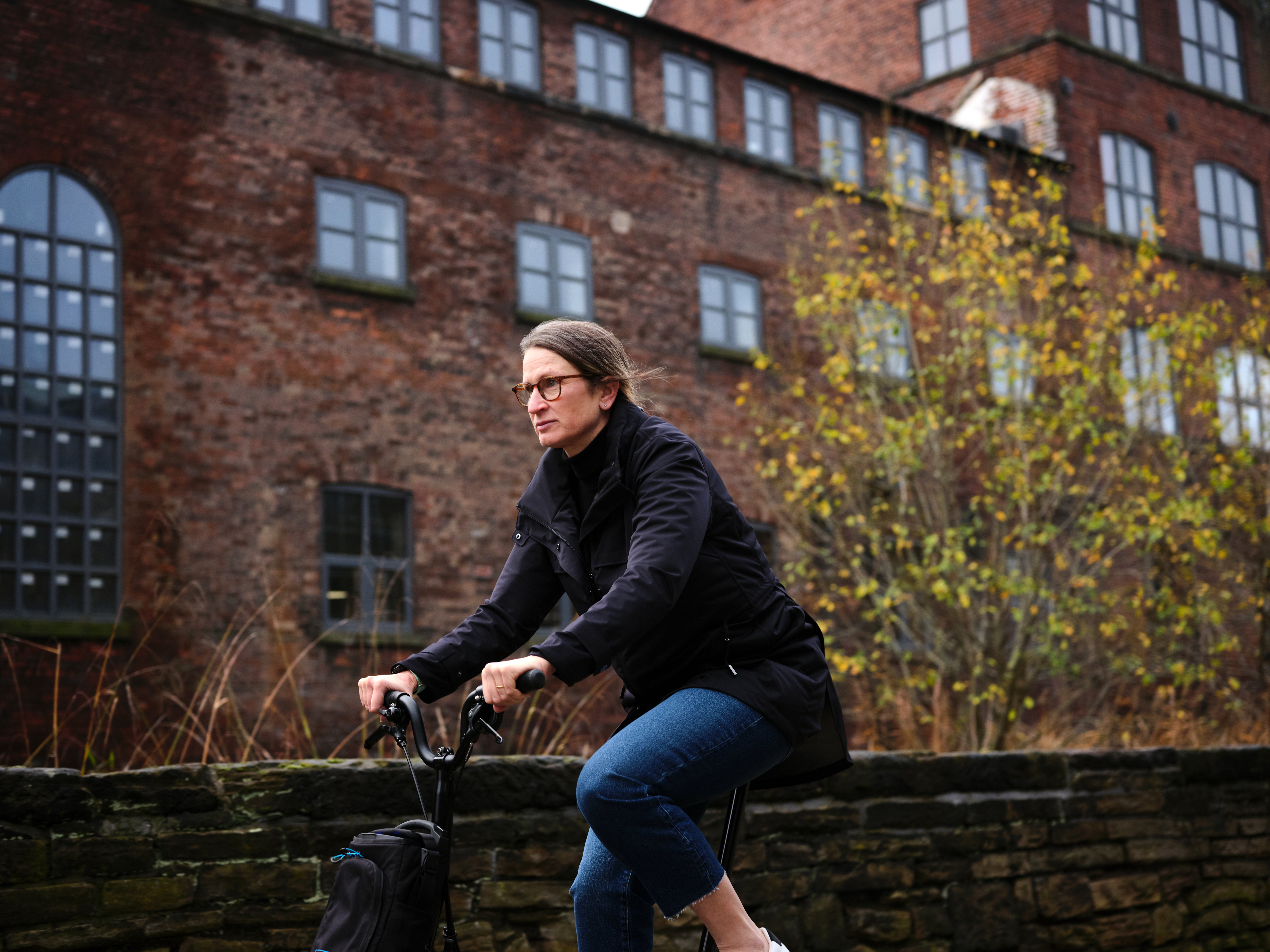 A woman cycling on a Brompton wearing the Brompton x Protected Species parka