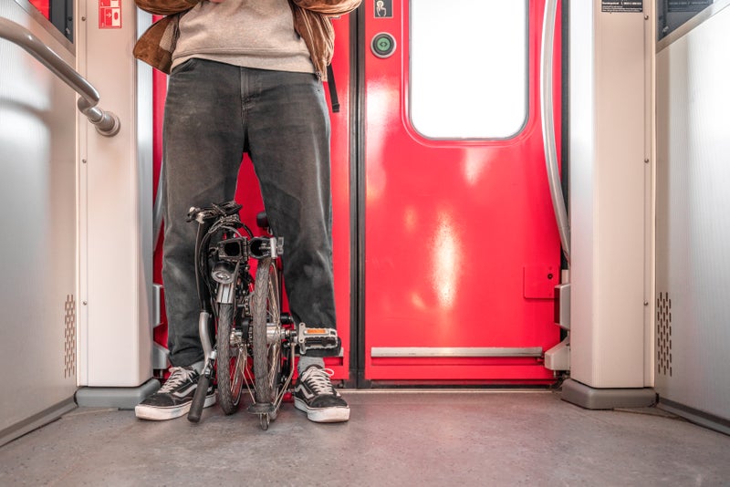 person stood with their brompton bike on train