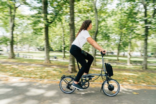 happy person cycling brompton electric p line through park