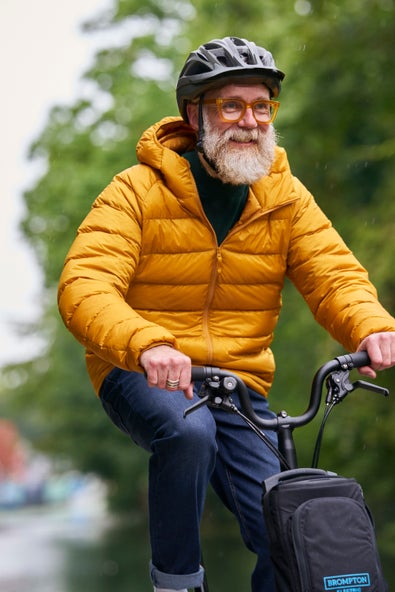 A happy smiling man riding a Brompton Electric