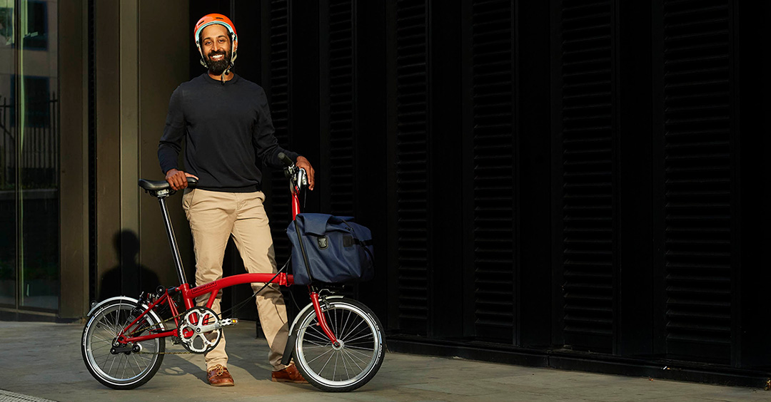 A happy man smiling with his Brompton folded bike