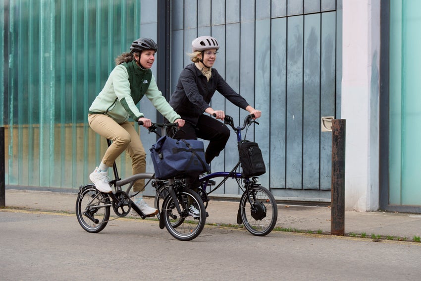 two people riding  Electric P T Line Explore 12-speed Bromptons on street