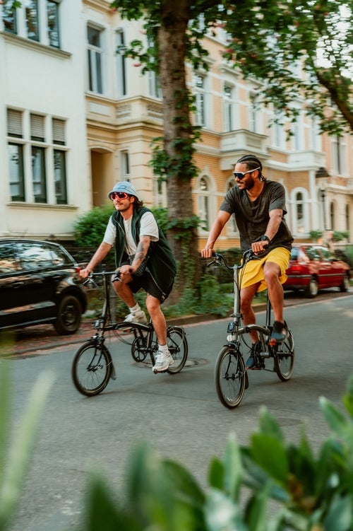two people riding brompton bikes through the streets in bonn