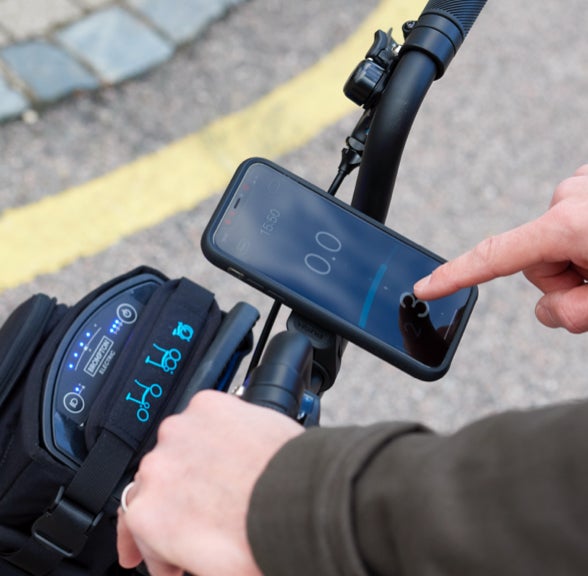 A person using the Brompton Electric app on their smartphone mounted to the handlebars of their Brompton Electric