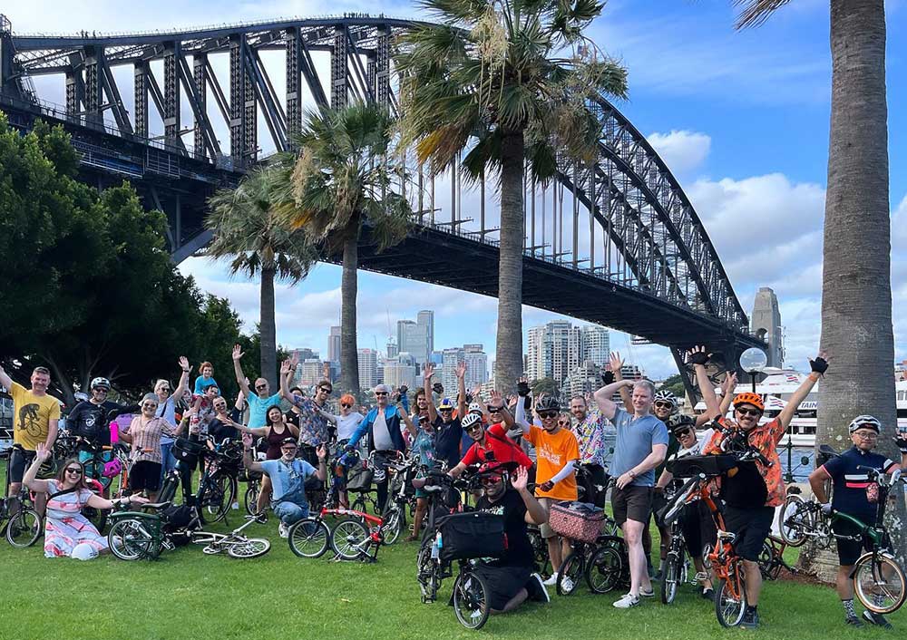 Fietsers met hun Brompton-fietsen voor de havenbrug van Sydney