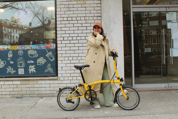 Person stood outside of a shop with a yellow Brompton bike