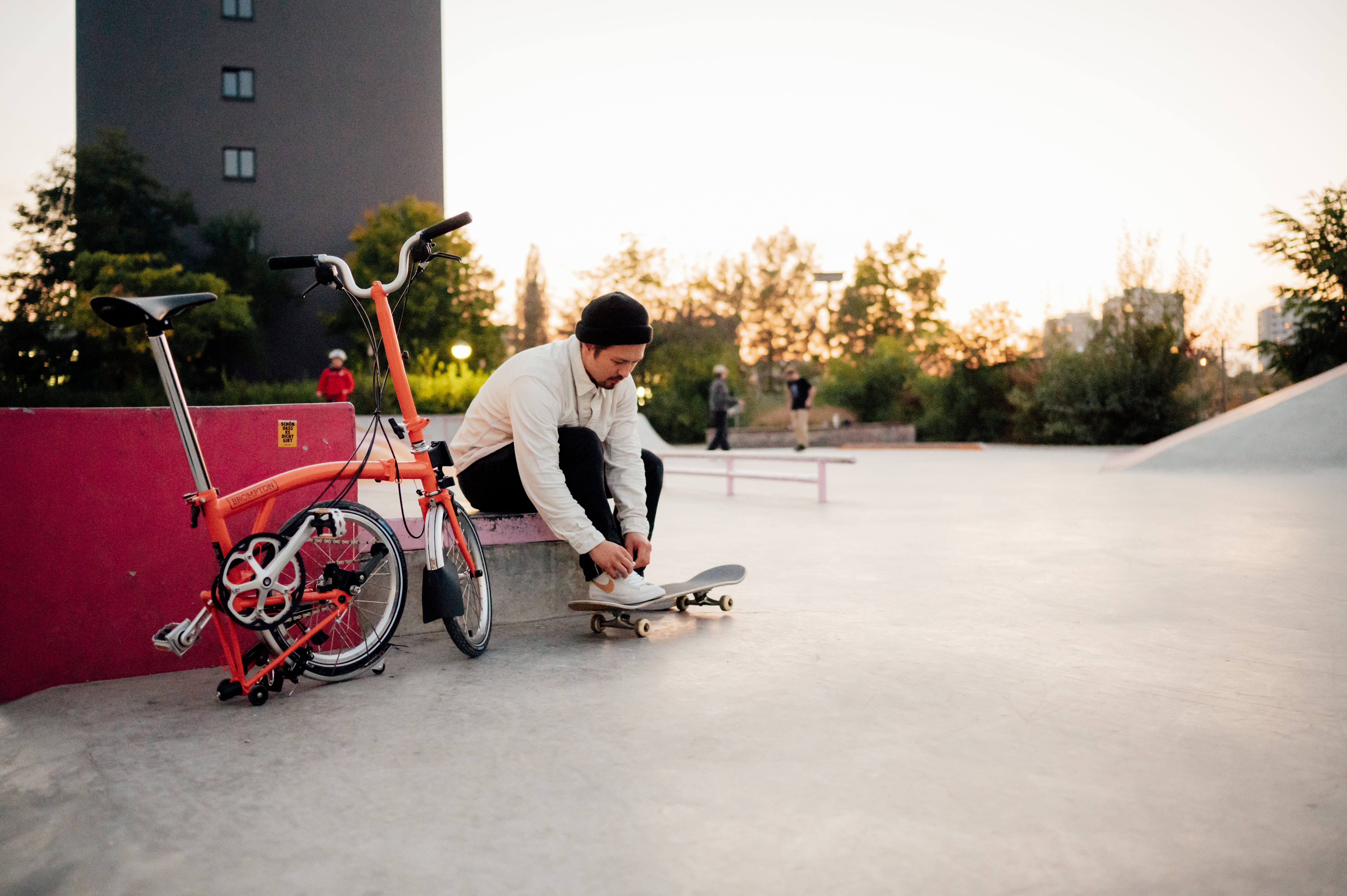 Skateboarder tying laces next to a folded Brompton bike