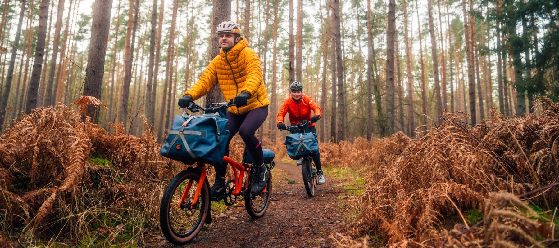 Two riders on G Line bikes in an autumnal forest