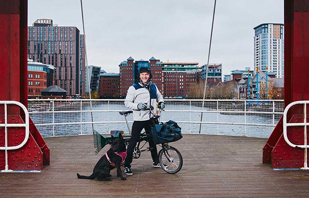 Man op een Brompton-fiets met zijn zwarte hond