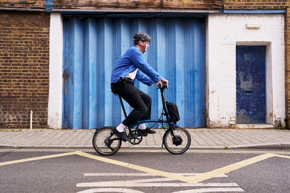 person riding brompton electric c line in front of a blue garage door