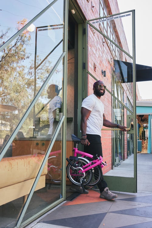 person carrying folded brompton bike out of a store