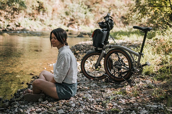 Person sat with folded G Line bike on river bank
