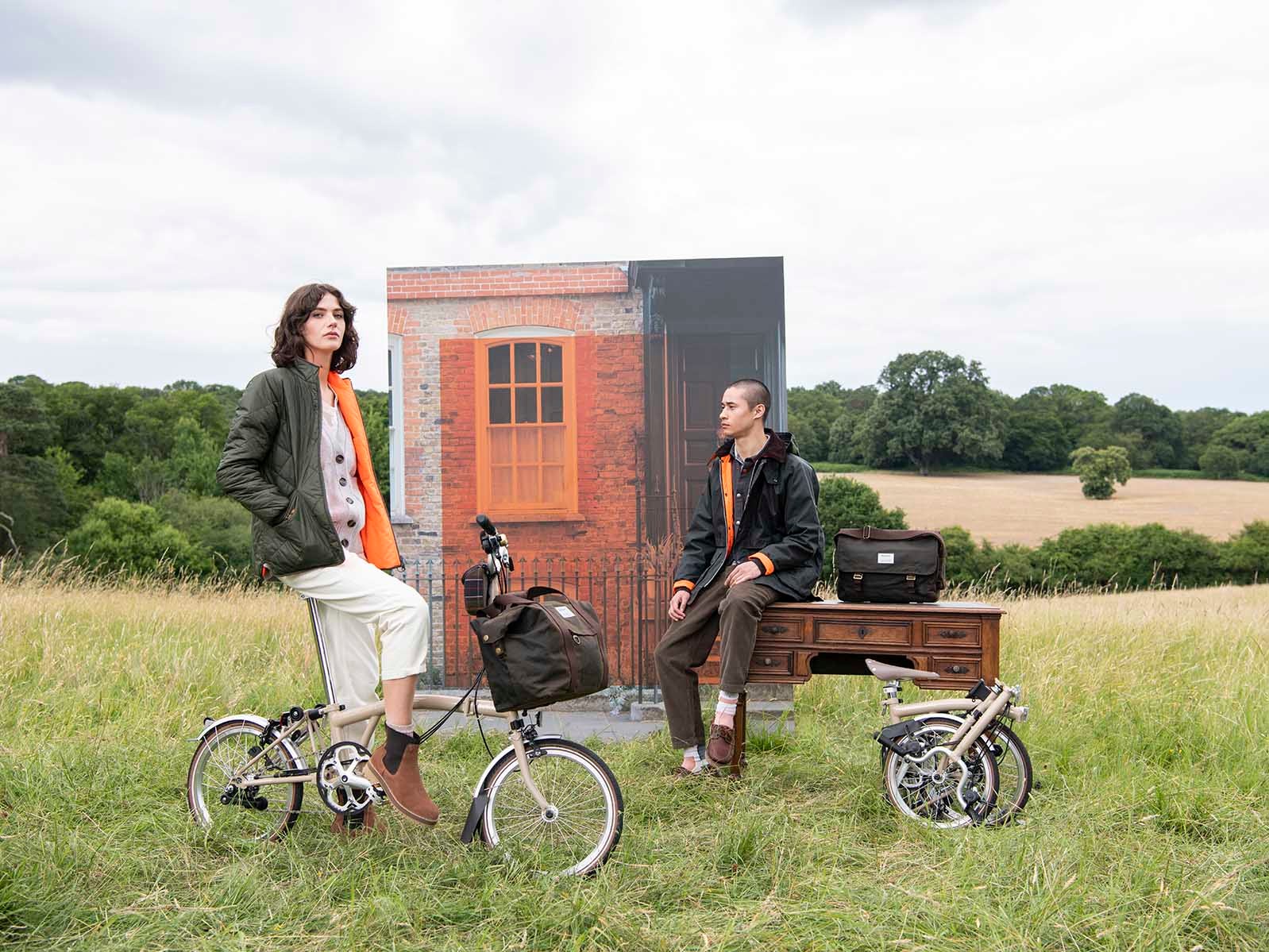 Two models posing in a field wearing the Barbour x Brompton collection