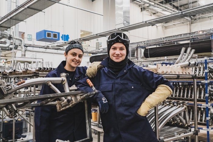 Twee Brompton-fabrieksmedewerkers die glimlachen tussen de machines