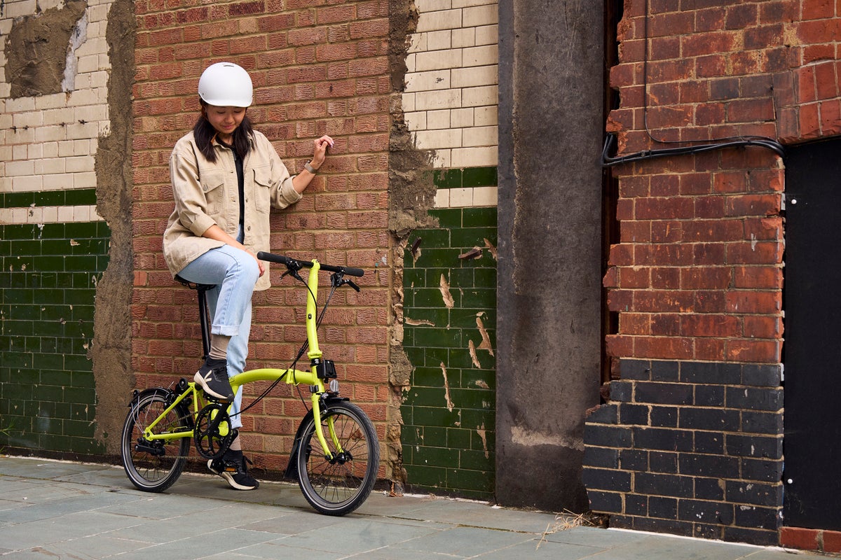 woman stood against wall with the brompton c line in yuzu lime