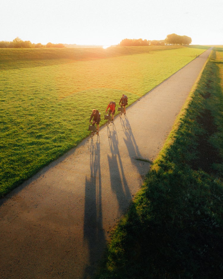 german roamers cycling by a green field on brompton x bear grylls bikes