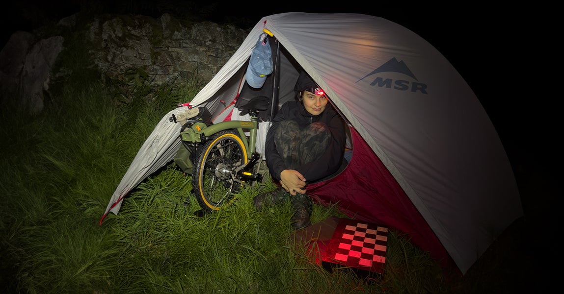 Photographer Dani KM in a tent with the Brompton x Bear Grylls folding bike