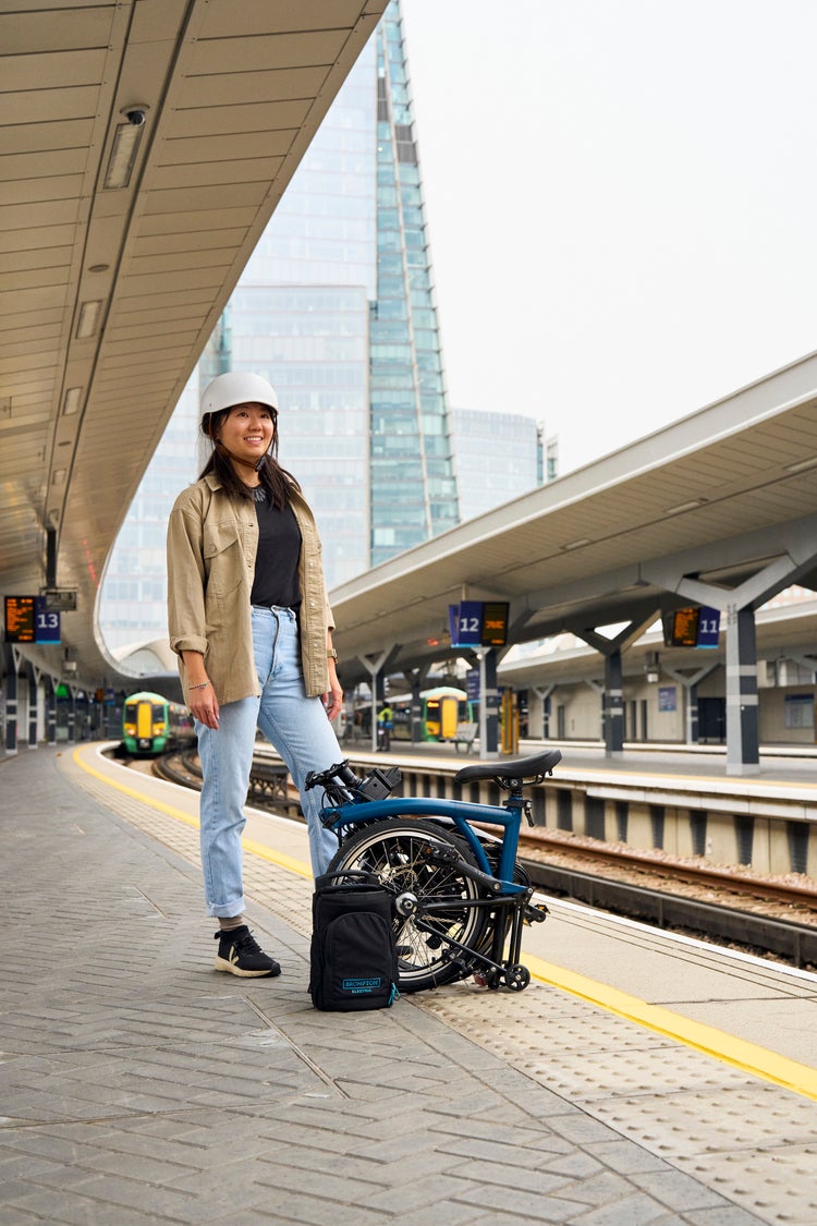person stood with folded brompton electric c line on london train platform