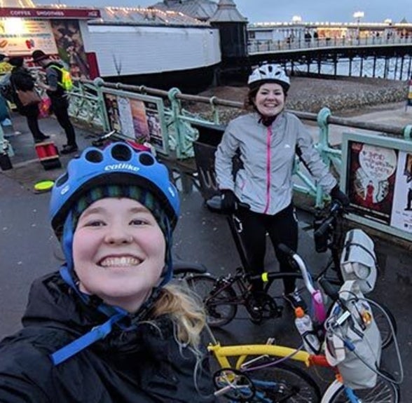 Oonagh and Matilda smiling and posing with their Bromptons on the Brighton Palace pier