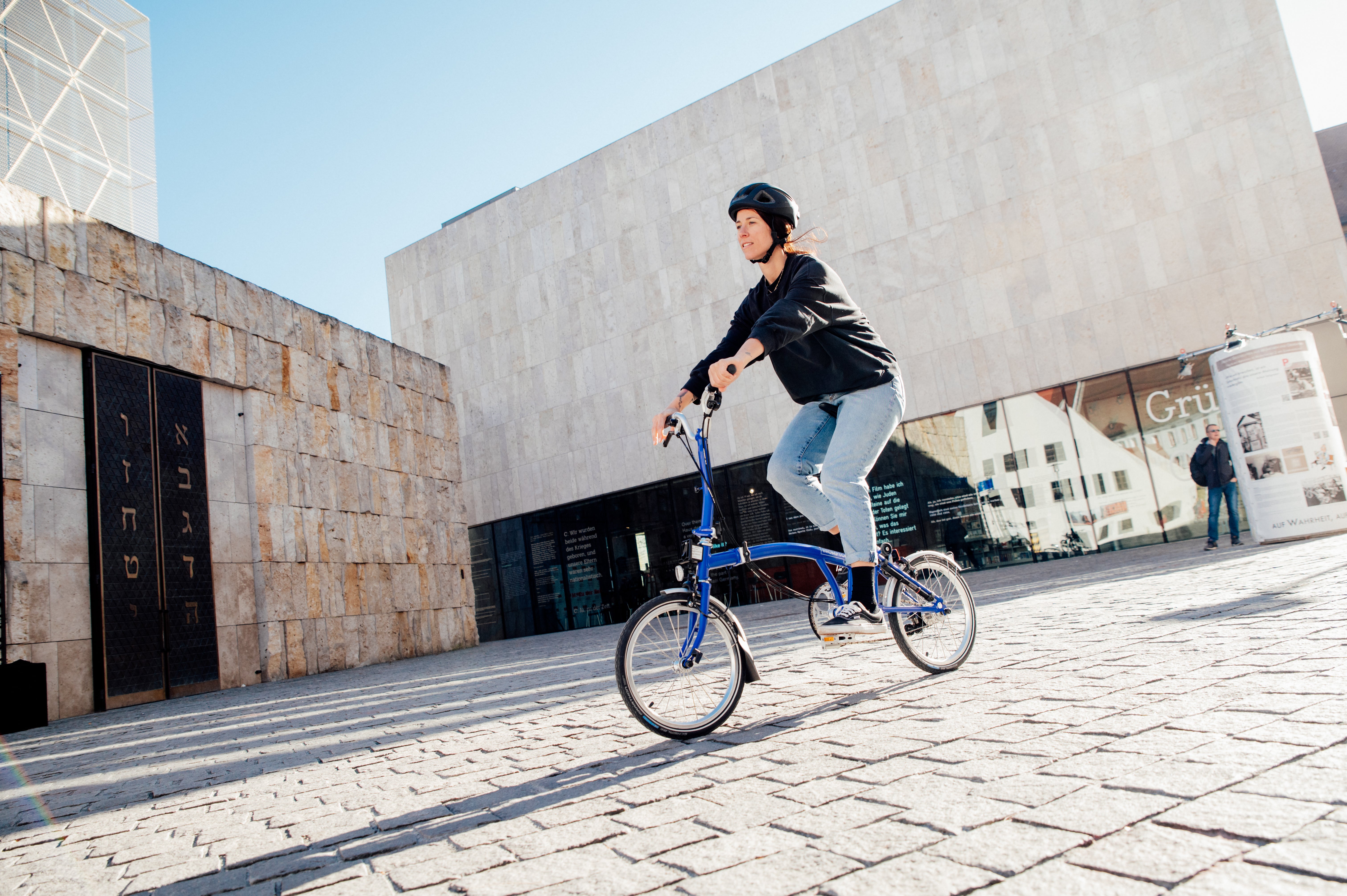 Image of a woman riding a blue Brompton