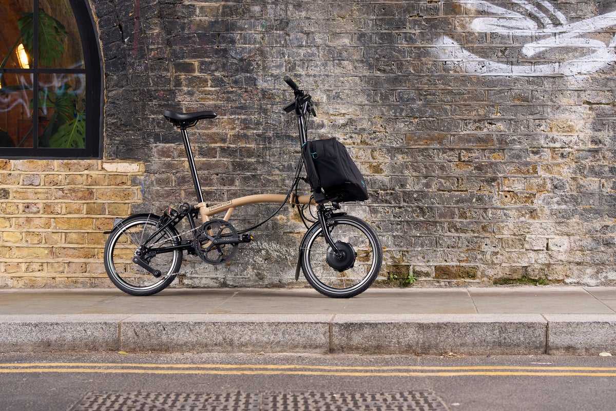 Brompton Electric C Line in Dune sand leaning against a wall