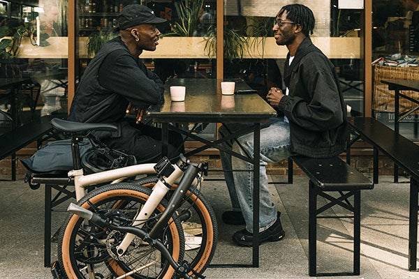 Two people sat outside coffee shop with folded Brompton G line