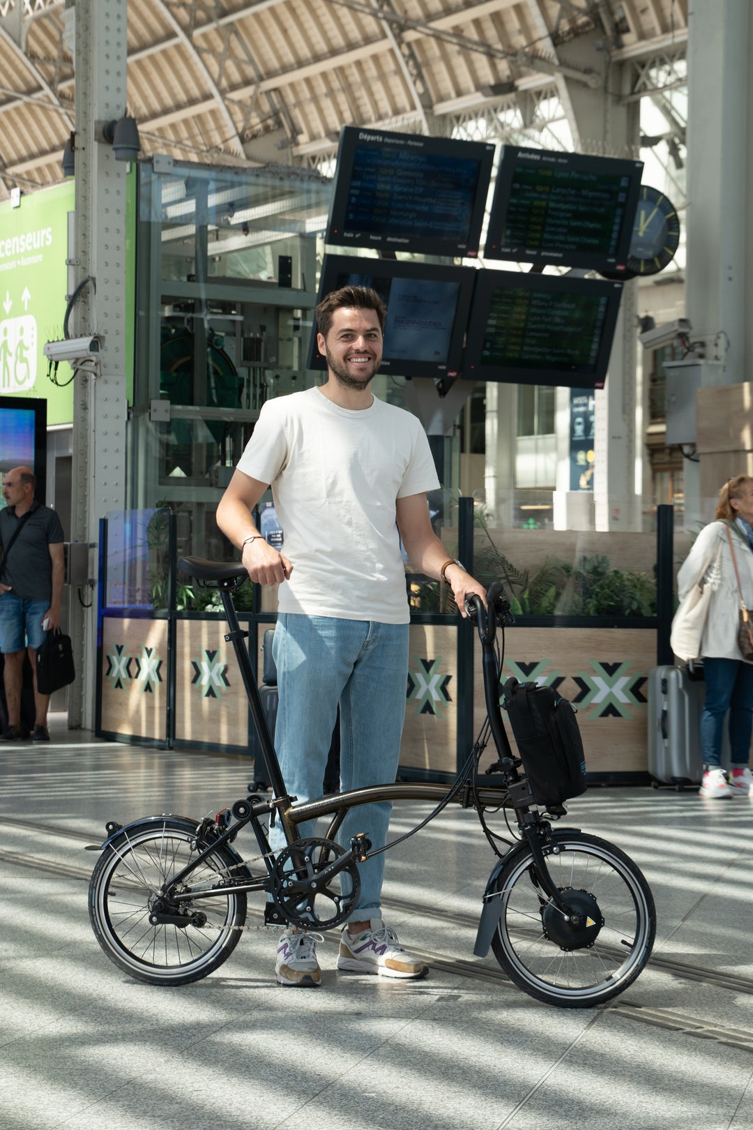 Une personne debout dans une gare avec son vélo Brompton.