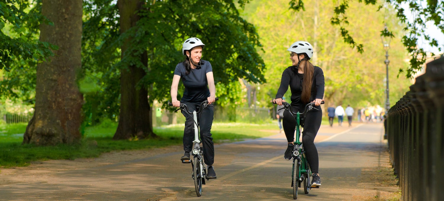 Two happy women riding their Brompton folding bikes