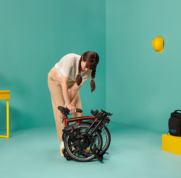 A gif of a woman unfolding a Brompton Electric C Line bike