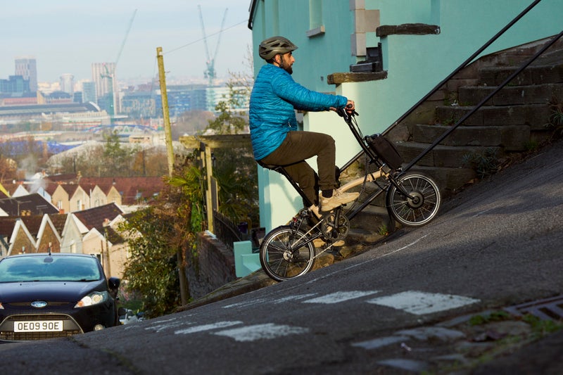 person riding electric c line 12 speed brompton uphill