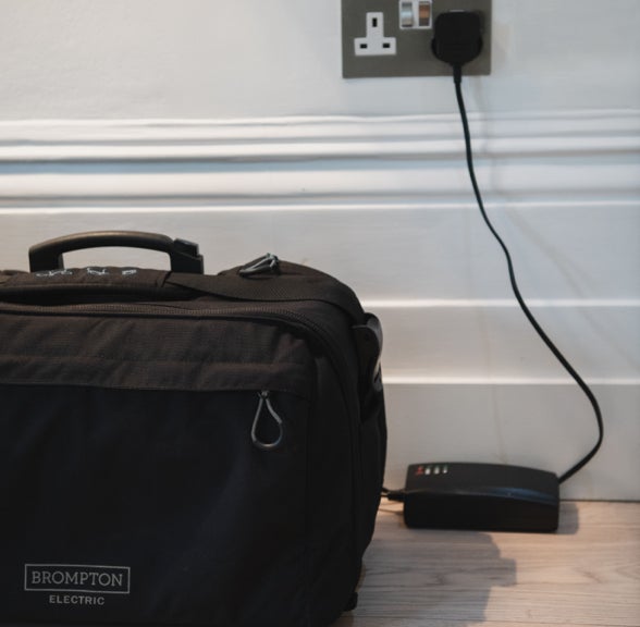 The Brompton Electric battery next to a smartphone on a coffeetable