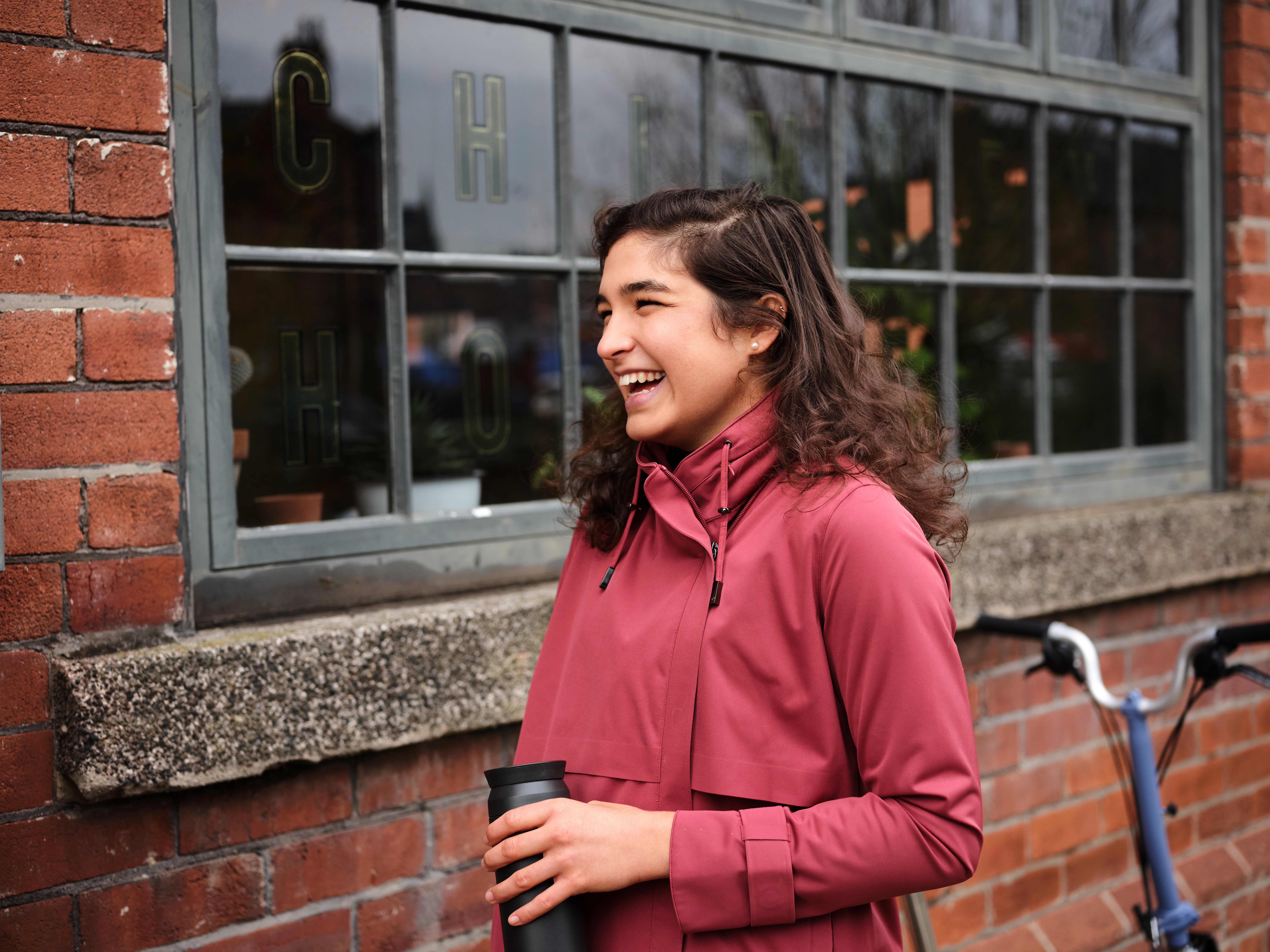 A young woman smiling and wearing the Brompton x Protected Species City Rider jacket
