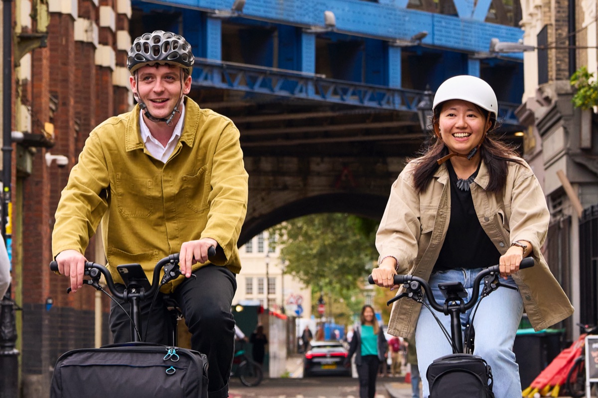 Two happy cyclists riding Brompton Electrics through the streets of London