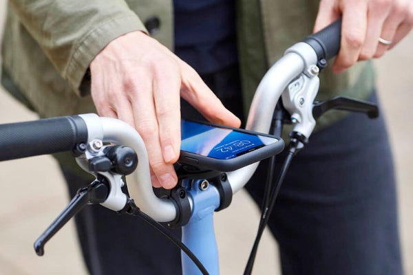 The Brompton Phone Mount holding a smartphone balanced on the handlebars of a Brompton folding bike