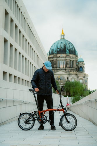 A cyclist standing with a Brompton C Line Explore folding bike in Berlin