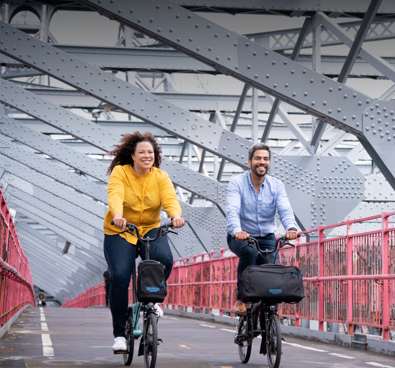 Two smiling people riding Brompton Electric C Lines