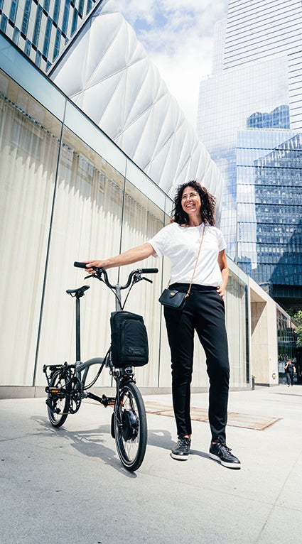 Woman stood with Brompton in a city environment.